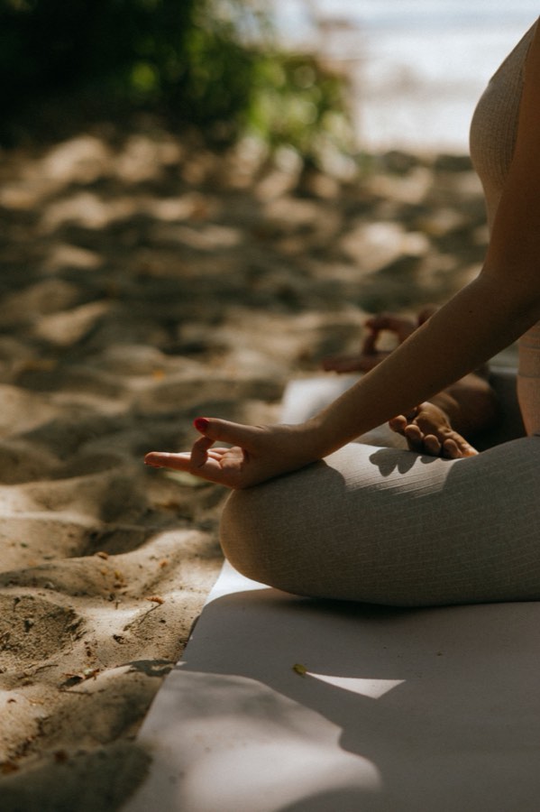 A person sitting in a meditation pose on a beach mat